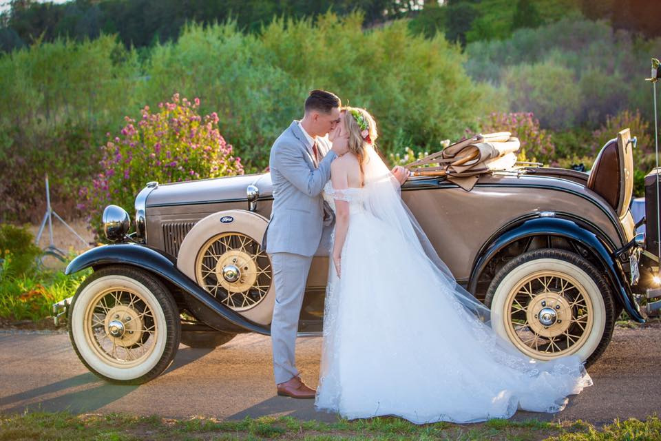 Couple just got married stands in front of old car